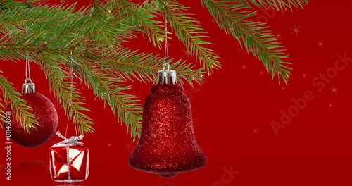 Image of snowflakes over fir tree with bell on red background