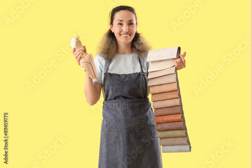 Female shoemaker with wooden shoe tree and fabric samples on yellow background