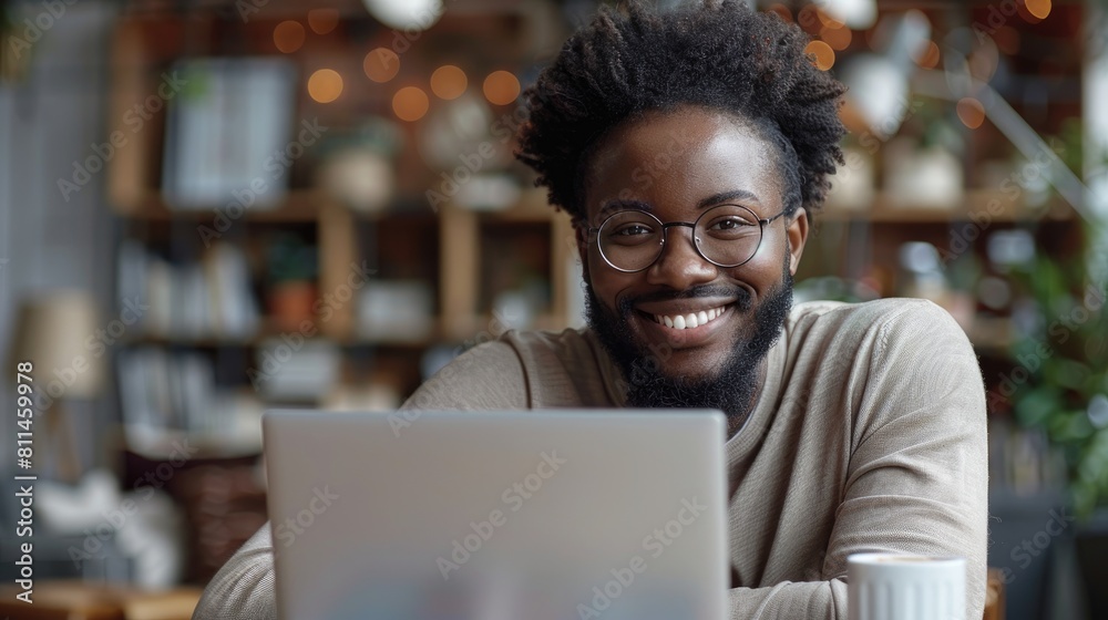 Smiling young african american man using laptop in home office Smiling young african american man using laptop in home office