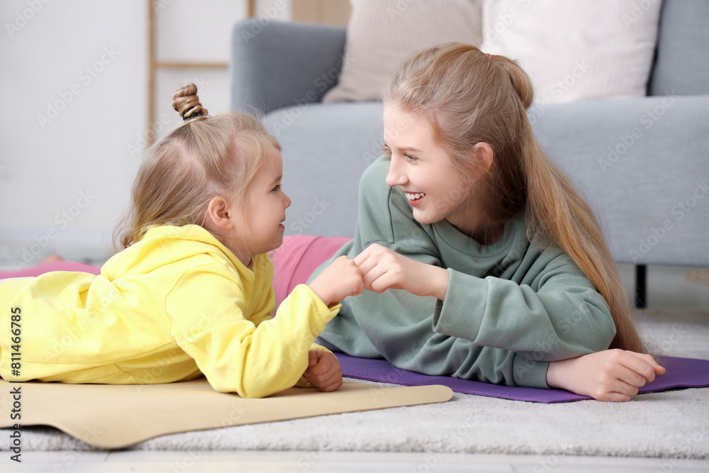 Sporty little girl with her mother bumping fists at home Sporty little girl with her mother bumping fists at home