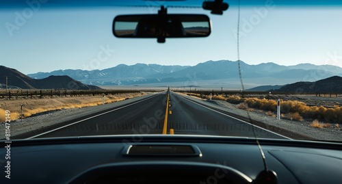 a car driving down a road in the desert with mountains in the background