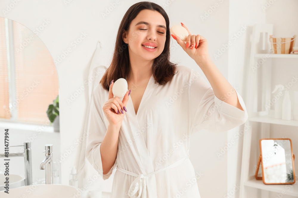 Young woman with soap bars in bathroom