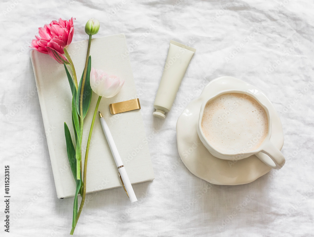 A cup of coffee, a personal diary, hand cream, tulips on a light background, top view A cup of coffee, a personal diary, hand cream, tulips on a light background, top view