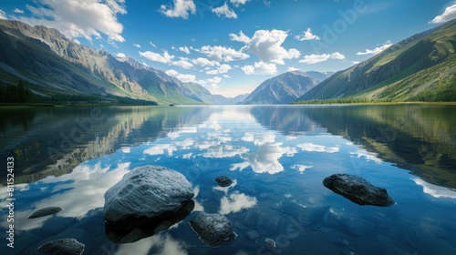Scenic mountain lake in summer morning Altai Stunning mirror image of mountains sky and white clouds Transparent water rocks at the lake bed photo
