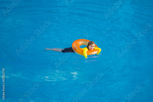 Kid playing with inflatable ring in swimming pool on hot summer day. Kid with inflatable ring in swimming pool. Summer vacation. Summer holiday. Summertime kids weekend.