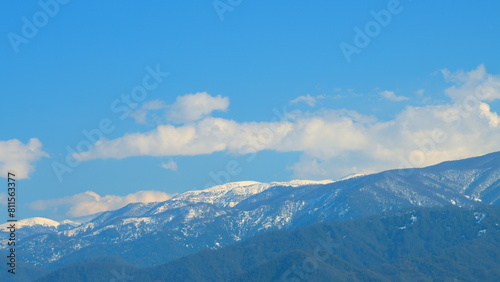 Fototapeta Naklejka Na Ścianę i Meble -  Snowy Hill With Moving Clouds Blown By The Wind. Beautiful Mountain Landscape In Winter. Timelapse.