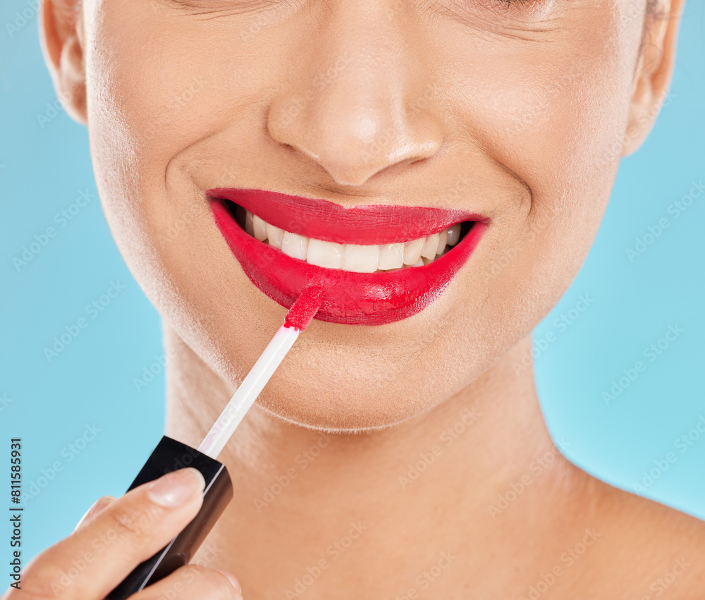 Woman, mouth and apply lipstick in studio, red lips and cosmetics makeup on blue background. Female person, beauty and confident smile for glossy grooming, skin care and makeover transformation Woman, mouth and apply lipstick in studio, red lips and cosmetics makeup on blue background. Female person, beauty and confident smile for glossy grooming, skin care and makeover transformation