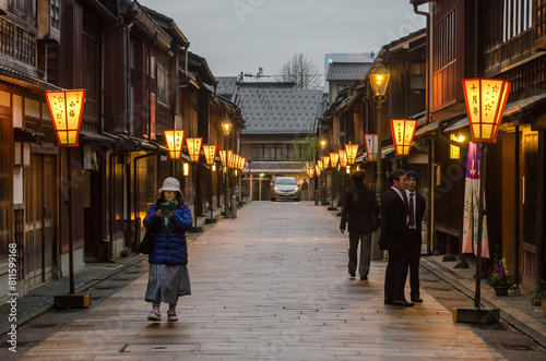 Fotografie A woman is walking down a narrow street in a japanese town