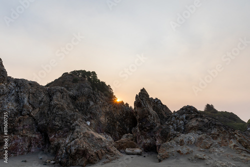 Sun peering over rocks at beach sunrise photo