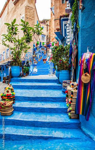 Beautiful moroccan blue streets in Chefchaouen. Bue city in Morocco with blue walls, architectural details, colorful flower pots and household items © Xandra