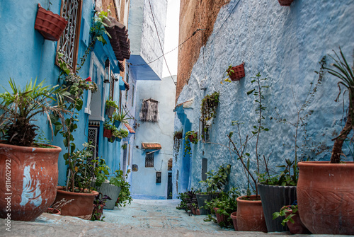 Beautiful moroccan blue streets in Chefchaouen. Bue city in Morocco with blue walls, architectural details, colorful flower pots and household items © Xandra