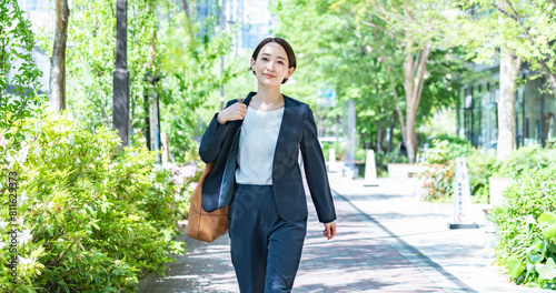 Fotografie 新緑の中を歩くスーツを着た女性