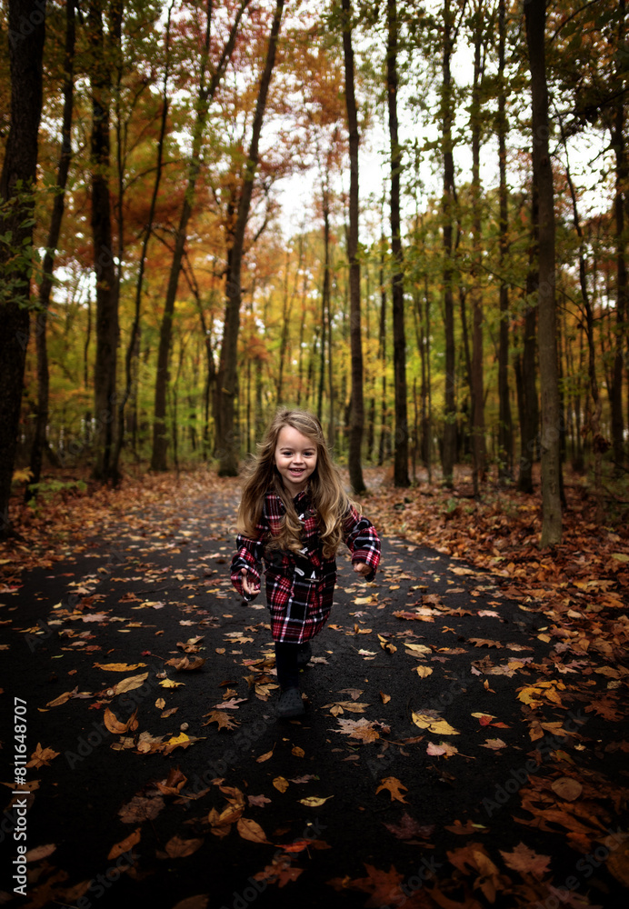 Happy young girl running down path with colorful leaves and trees Happy young girl running down path with colorful leaves and trees