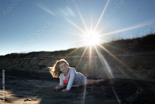 Happy young girl playing in sand on bright sunny beach dunes photo