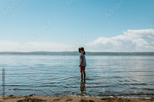 Young girl stands in Bay of Fundy, New Brunswick on a sunny day photo