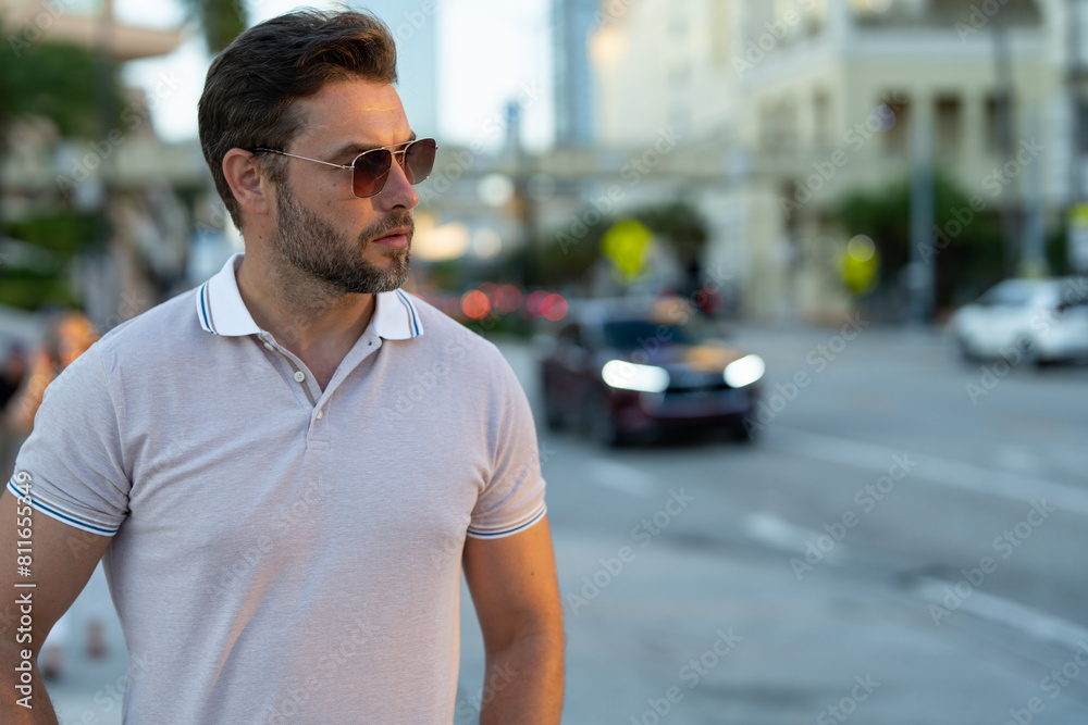 Man model in fashion in stylish polo walking on the city. Guy walks on the street. Urban fashion man in city walking street. Portrait of stylish handsome man outdoors. Portrait of attractive man Man model in fashion in stylish polo walking on the city. Guy walks on the street. Urban fashion man in city walking street. Portrait of stylish handsome man outdoors. Portrait of attractive man