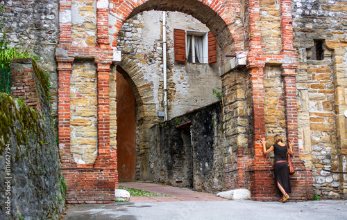 the woman leaning on Porta Rugo in the city center of Belluno in Italy
