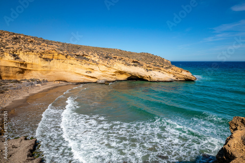 Beautiful cove in the Cabo Cope and Puntas de Calnegre Regional Park, with crystal clear waters and yellow rock cliffs photo