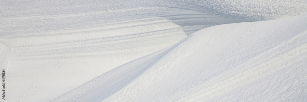 Beautiful winter background with snowy ground. Natural snow texture. Wind sculpted patterns on snow surface. Wide panoramic texture for background and design. Beautiful winter background with snowy ground. Natural snow texture. Wind sculpted patterns on snow surface. Wide panoramic texture for background and design.
