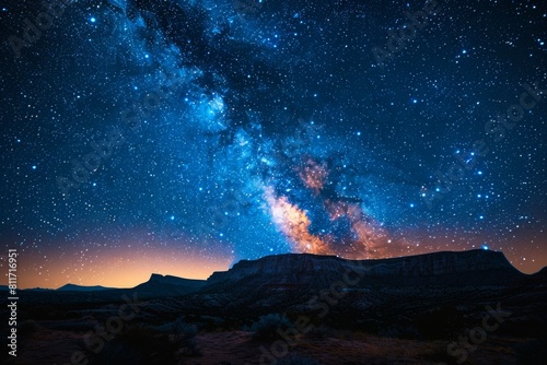 The Milky Way galaxy stretches across the sky over a rocky desert landscape, inspiring awe in the cosmos