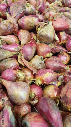Close up pile of fresh red onions placed together in local market as a background.