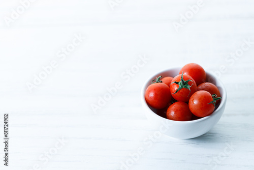red cherry tomato in white ceramic bowl on white background