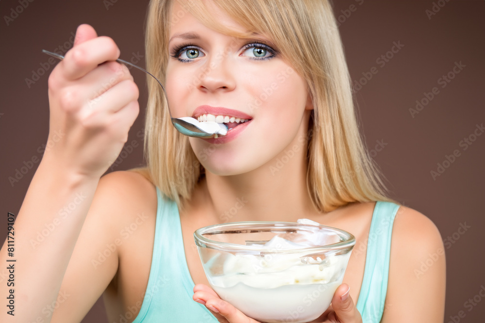 girl with yogurt. young cheerful blonde girl eating white yogurt with a transparent plate, on a brown background, healthy concept girl with yogurt. young cheerful blonde girl eating white yogurt with a transparent plate, on a brown background, healthy concept