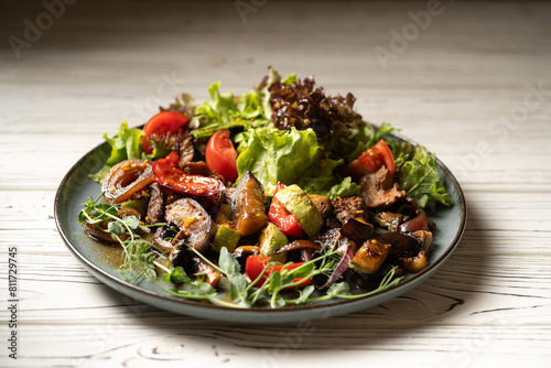 hot salad with beef fillet and grilled vegetables served on a plate on a light table in a restaurant