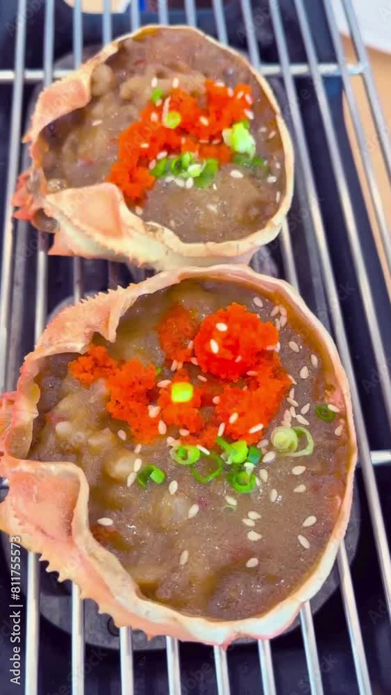 Kanimiso (miso crab kani) is a popular grilled Japanese seafood dish made from miso and crab meat mixed with crab shells grilled on a charcoal grill and topped with salmon roe and scallions.- video