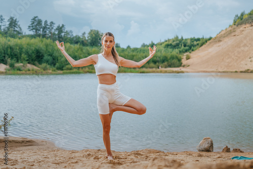 Принти на полотні Woman in a Tree Pose (Vrikshasana) by a river, wearing a white yoga outfit, show