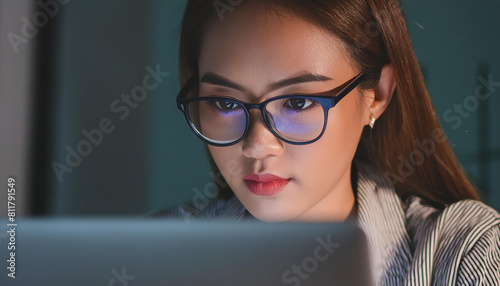 Close up of eyes woman wearing glasses working on laptop computer late at night in office.