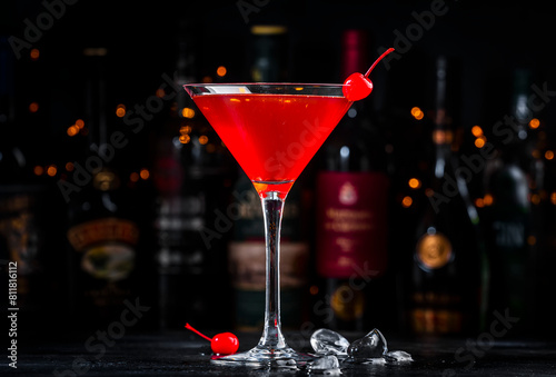 Red alcoholic cocktail drink with cherry on dark background, bar counter with bottles © 5ph