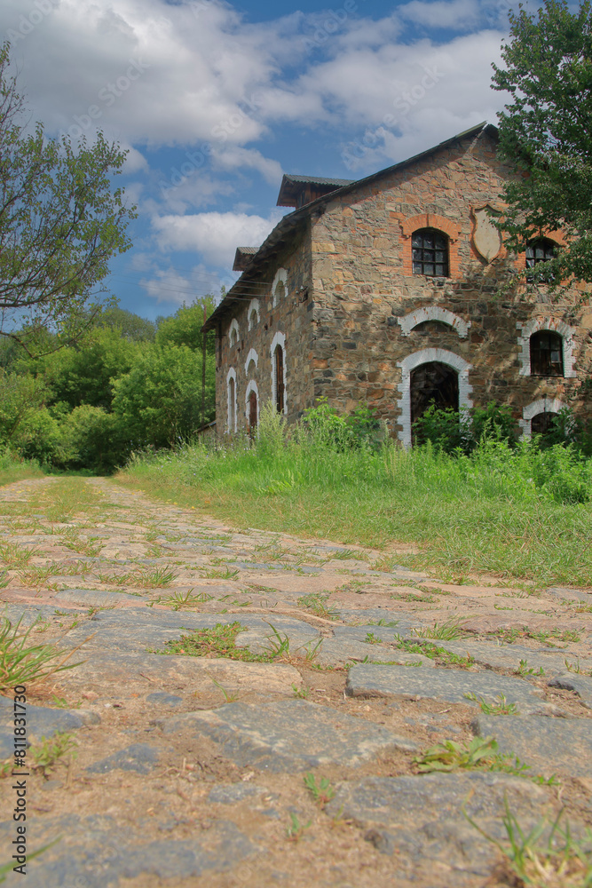 Obraz premium Stone barn next to a paved rural road.