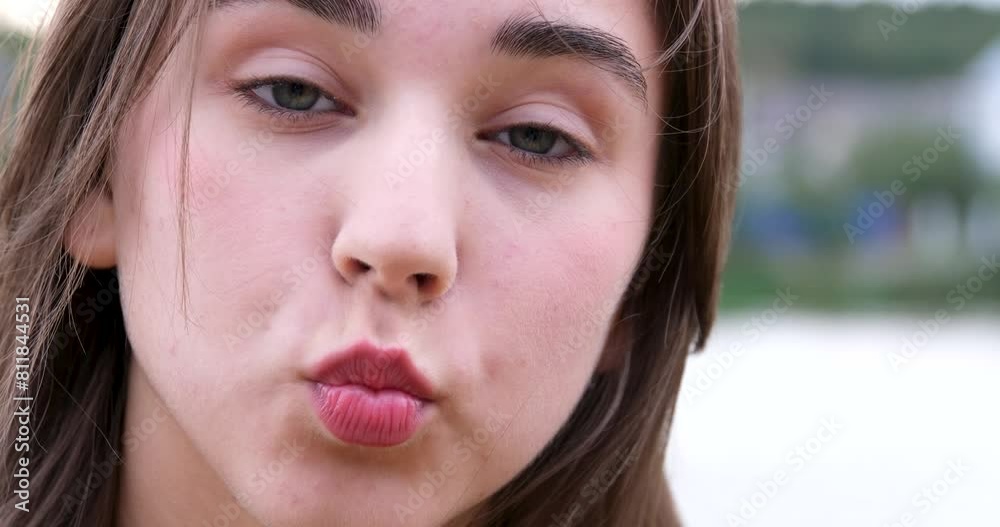 The girl blows a kiss, shows her tongue, makes faces. Cute female model with light makeup against the backdrop of nature, lake The girl blows a kiss, shows her tongue, makes faces. Cute female model with light makeup against the backdrop of nature, lake