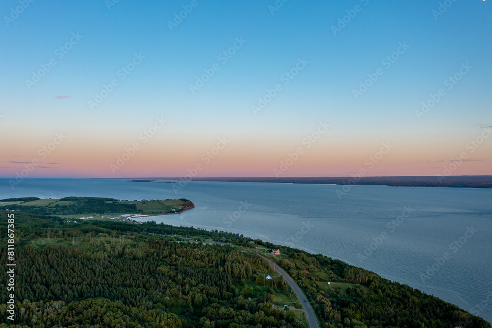 Wide river in wooded valley after sunset in Quebec, Canada. Colorful sunset sky. Drone type.