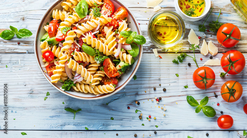 Bowl with tasty pasta salad and ingredients on light