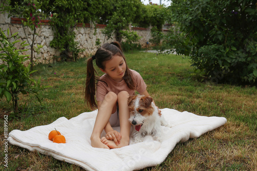 Little girl playing outside with her wire haired jack russell terrier pup. Six year old and a furry friend playing in the backyard. Close up, copy space, background.