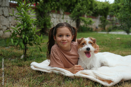 Little girl playing outside with her wire haired jack russell terrier pup. Six year old and a furry friend playing in the backyard. Close up, copy space, background.