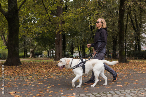 Photography Woman with visual impairment walking with her guide dog through the city park