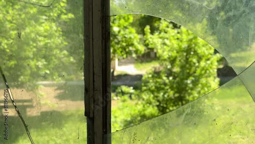 View outside from the inside of the house through broken glass window. Shards of glass in a broken window.