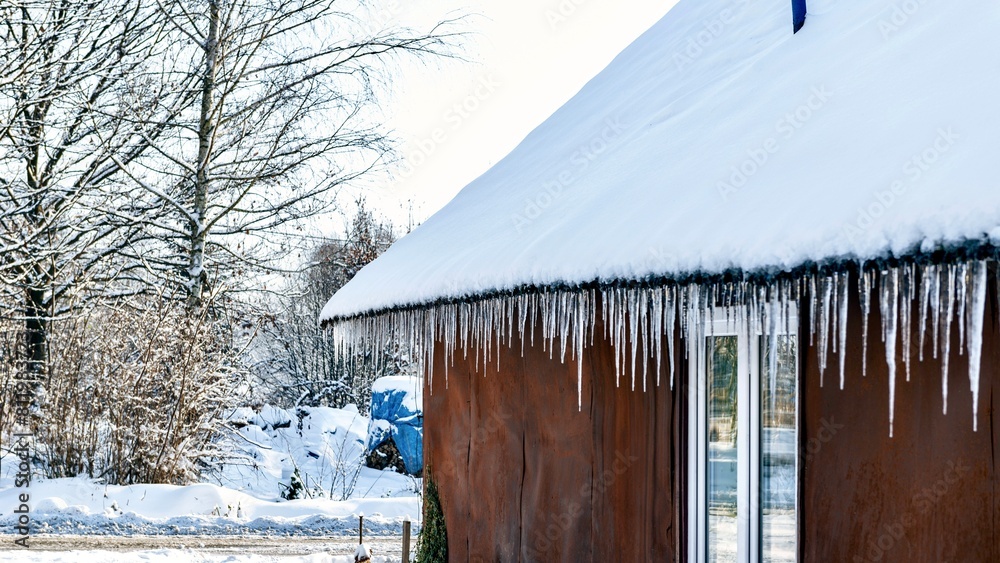 Icicles hang from the roof of the house in winter.