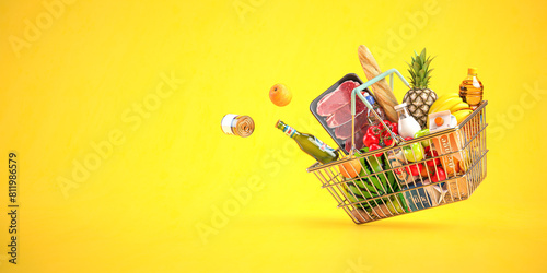 Shopping basket full of grocery products, food and drink on yellow background. photo