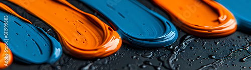 In a captivating close-up, layers of thick orange and blue paint intertwine and meld together upon a velvety black canvas, creating a dynamic and visually arresting composition that commands attention