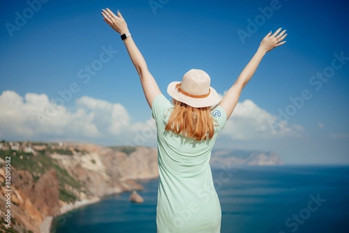 Woman tourist sky sea. Happy traveler woman in hat enjoys vacation raised her hands up