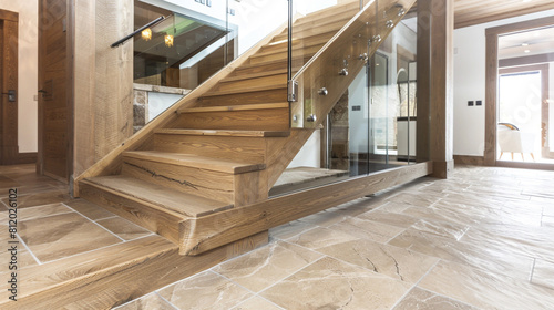 Sophisticated wooden staircase with glass panels set in a luxurious modern home with natural stone floors
