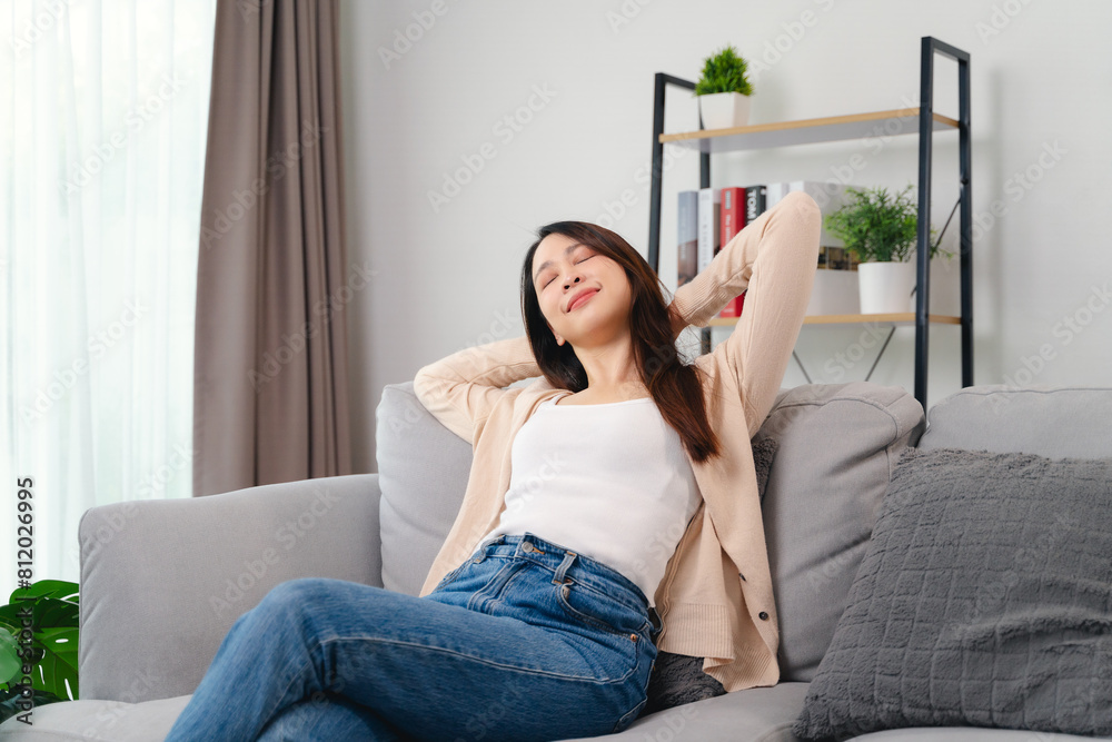 Fototapeta premium A woman is sitting on a couch with her arms crossed and a relaxed expression on her face