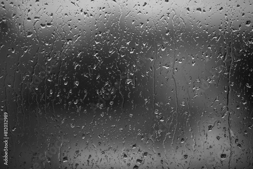 Rain drops on window glass closeup macro. Black and white abstract background texture with rain drop
