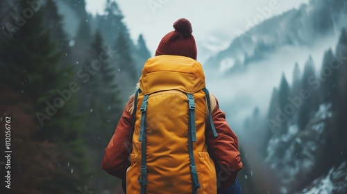 Osoba w żółtym plecaku spaceruje po zimowym krajobrazie, pozostawiając ślady stóp w śniegu photo
