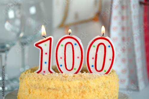 Celebration cake with burning candle number 100