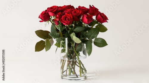 A bunch of vibrant red roses arranged in a transparent glass vase set against a crisp white backdrop